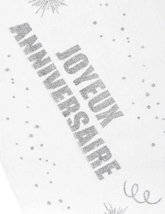 Gros plan sur l'inscription du chemin de table organza Joyeux anniversaire argent pailleté