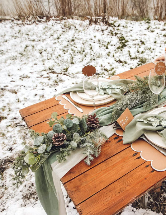 Mise en scène sur une table de fête de la descente de sapin et eucalyptus avec pommes de pin