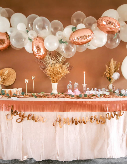 Mise en situation sur une table d'anniversaire du kit arche de 70 ballons rose gold avec eucalyptus et roses