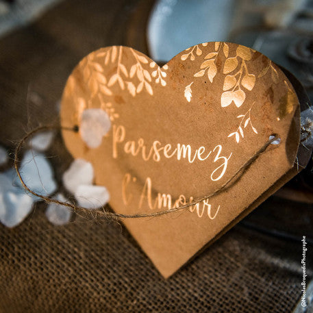 Gros plan sur l'écriture bronze et les motifs du sac coeur végétal parsemez l'amour pour mariage kraft et bronze