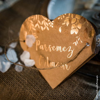 Gros plan sur l'écriture bronze et les motifs du sac coeur végétal parsemez l'amour pour mariage kraft et bronze