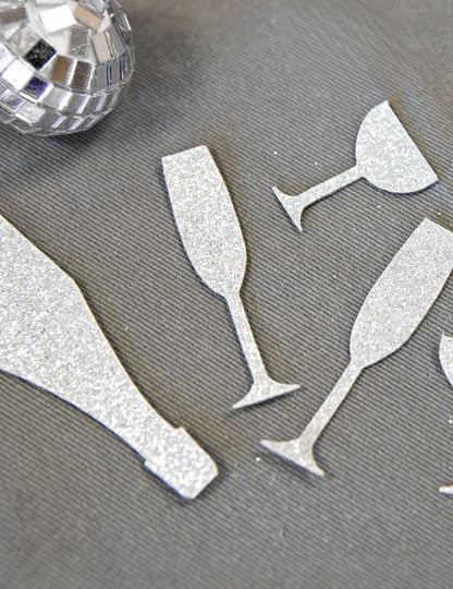 Gros plan sur la texture pailletée des confettis de table champagne argentés coupes et flûtes