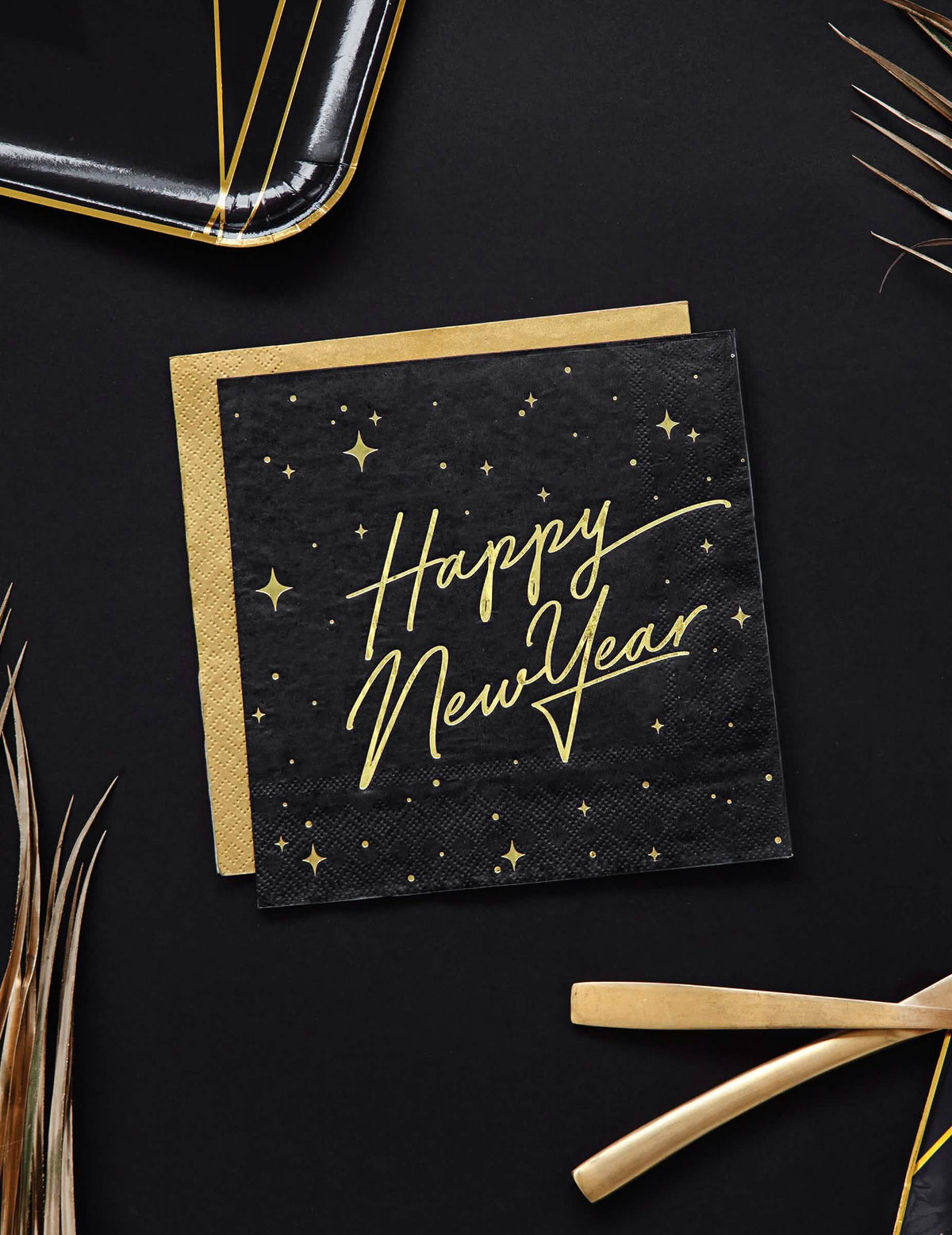 Горен изглед на черни и златни хартиени салфетки Happy New Year с декор със звезди