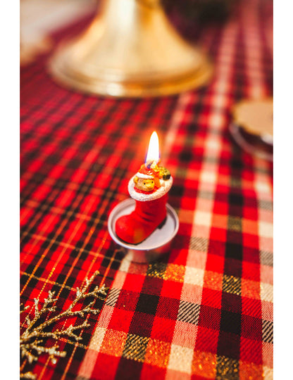 Zoom sur la bougie allumée des 3 bougies botte du père noël avec ourson