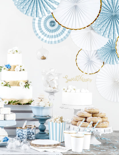 Mise en situation sur un buffet de fête des 3 rosaces en papier blanches et dorées pour décoration