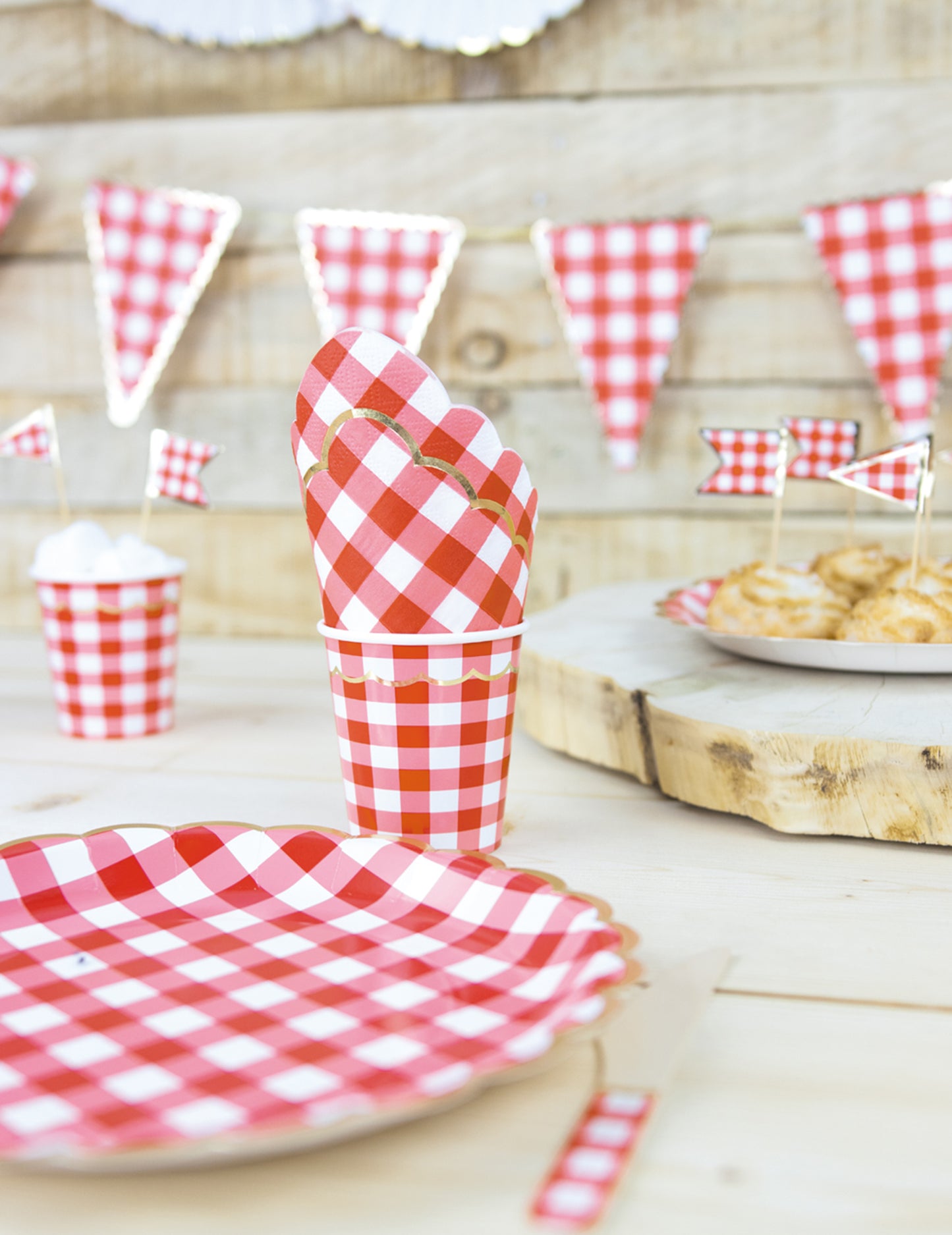 Mise en situation avec gobelet et serviette des assiettes festonnées en carton vichy rouge et blanc