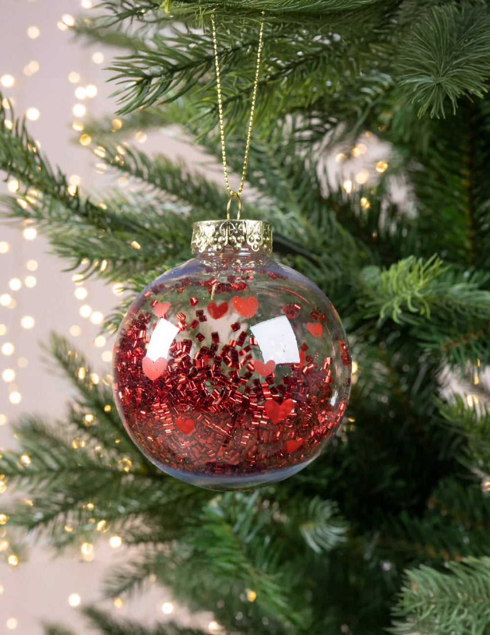 Vue suspendue dans un sapin de la boule de noël avec cœurs rouges et confettis brillants