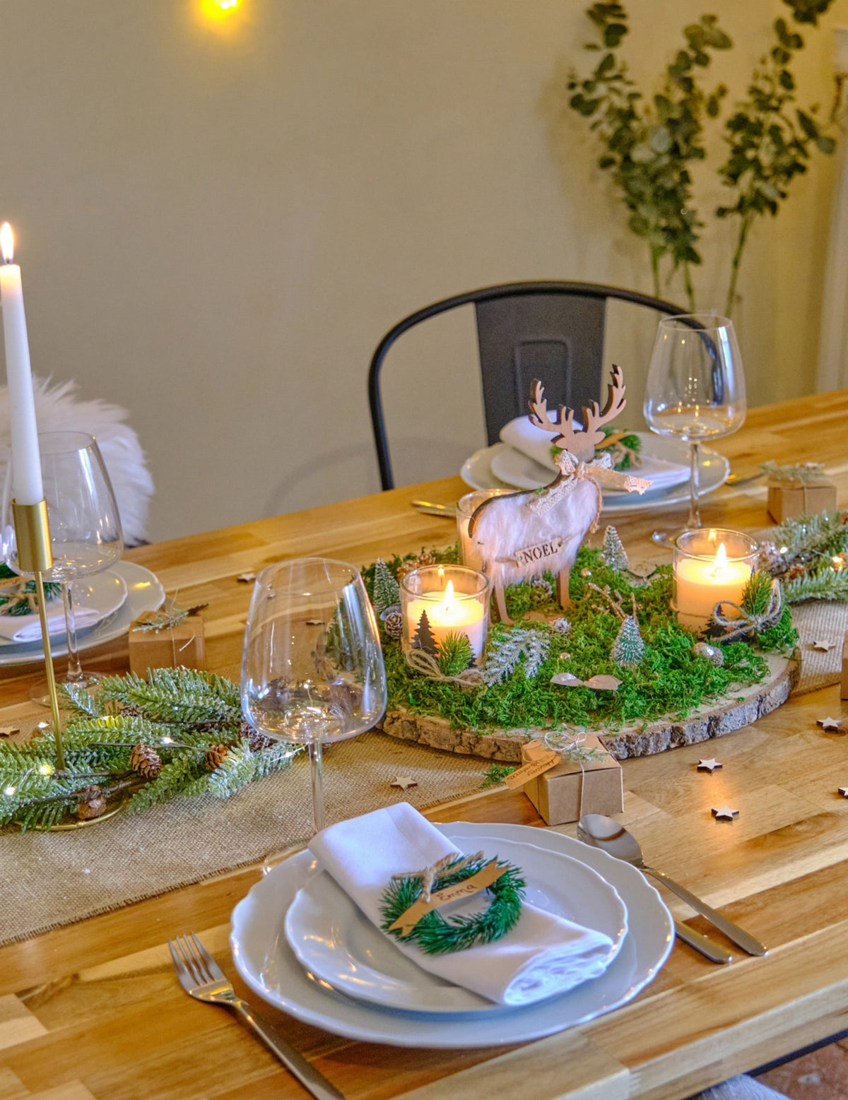 Mise en scène sur une table de fête de la branche de sapin enneigée avec pommes de pin
