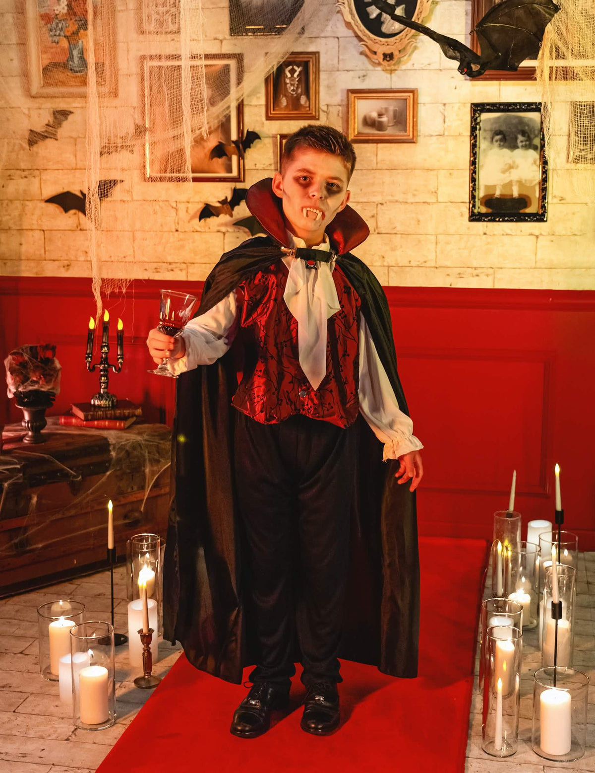 Сценка на елегантен вампирски костюм за момче в декор за halloween със свещи