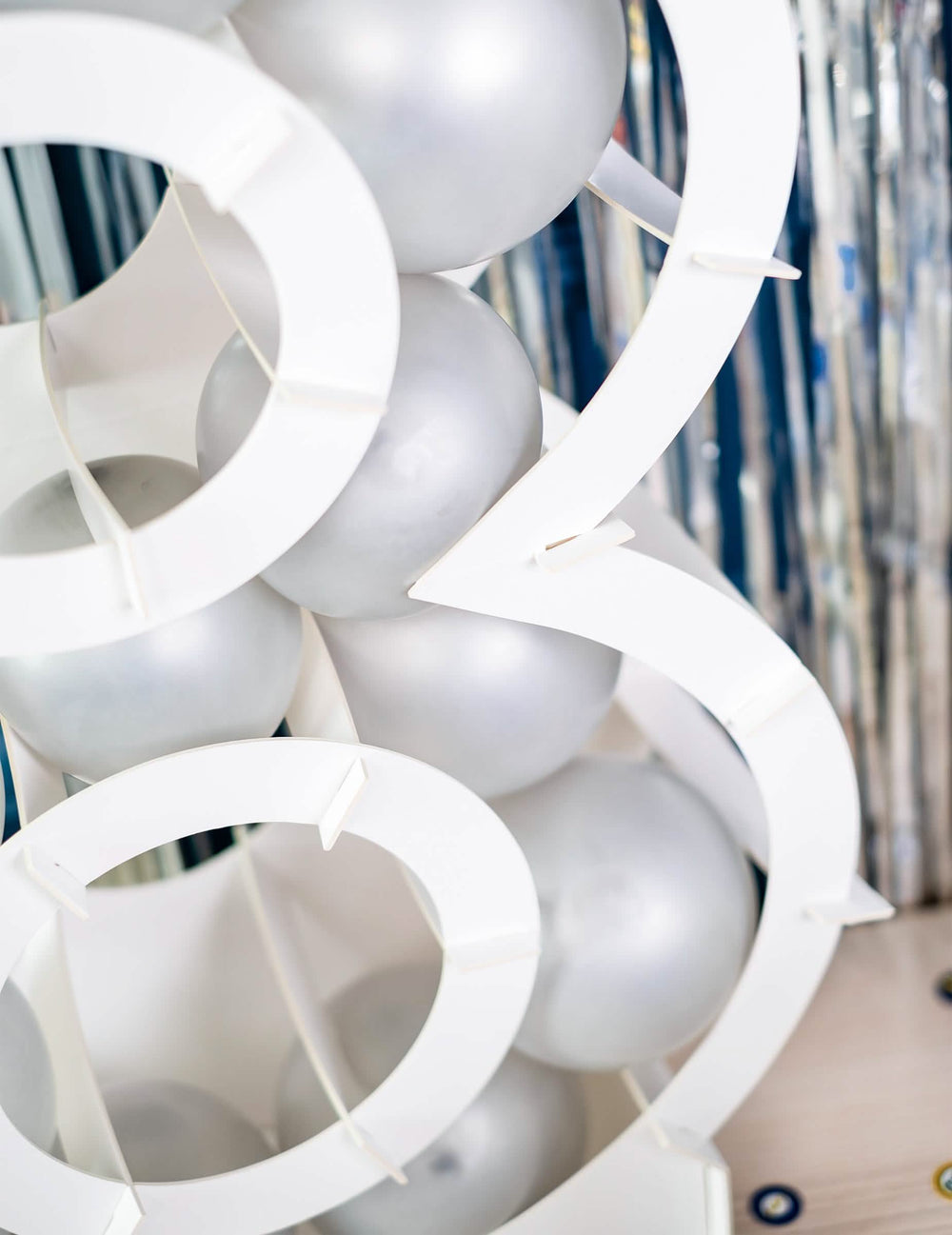 Zoom sur le garnissage de ballons de la structure chiffre pour décoration de fête blanc en carton à garnir