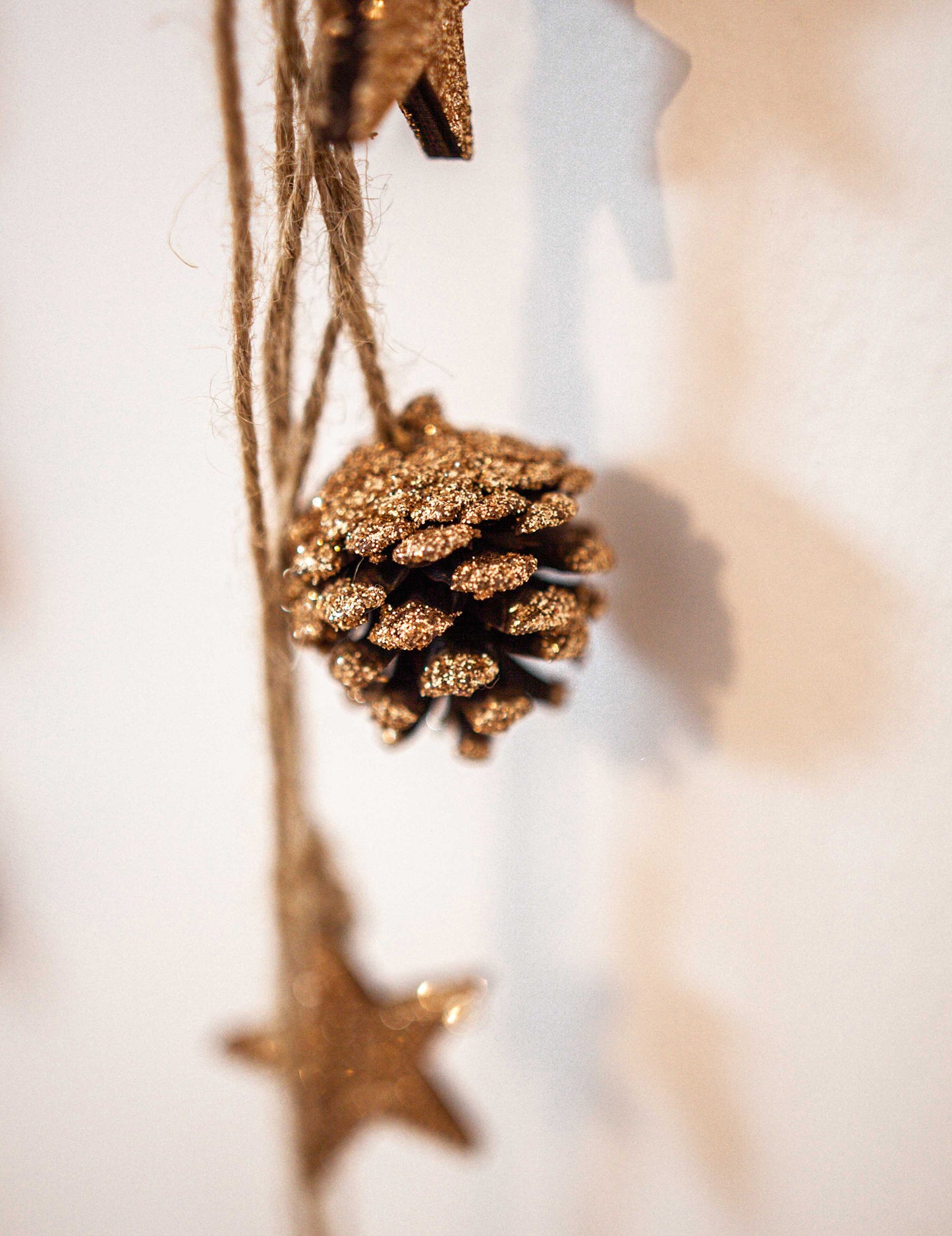 Gros plan sur la pomme de pin pailletée de la suspension pommes de pin et étoiles bois pour décoration paillettes cuivre