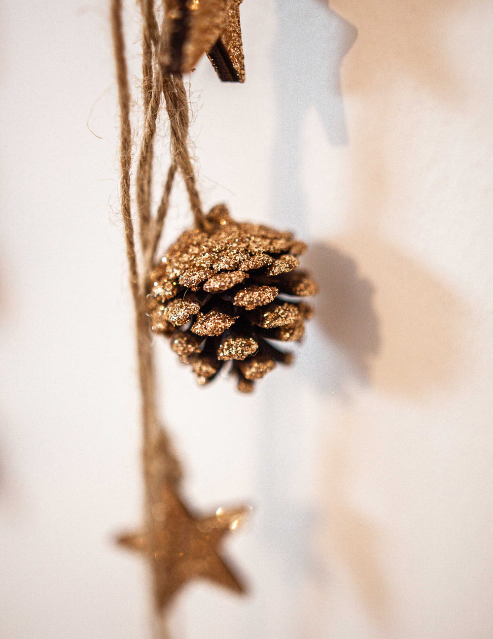 Gros plan sur la pomme de pin pailletée de la suspension pommes de pin et étoiles bois pour décoration paillettes cuivre