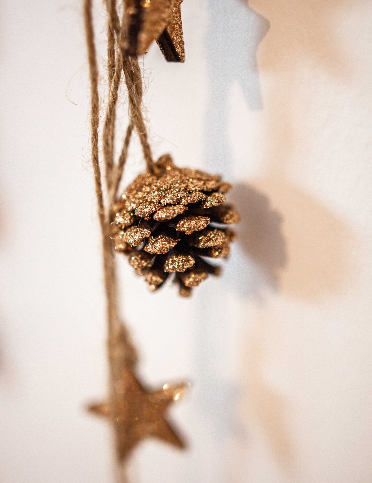 Gros plan sur la pomme de pin pailletée de la suspension pommes de pin et étoiles bois pour décoration paillettes cuivre